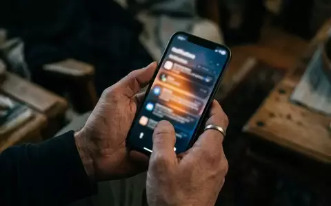 Nahaufnahme einer Hand, die ein Smartphone hält, auf dessen Display eine unscharfe Benachrichtigung zu sehen ist. - Foto: über boerse-global.de