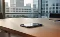 Ein Smartphone auf einem minimalistischen Holztisch in einem modernen Büro bei natürlichem Licht. - Foto: über boerse-global.de
