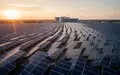 Weitläufiger Solarpark bei Sonnenuntergang mit einem modernen Rechenzentrum im Hintergrund. - Foto: über boerse-global.de