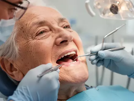 Nahaufnahme einer zahnärztlichen Untersuchung bei einem älteren Patienten in einer hellen Praxisumgebung. - Foto: über boerse-global.de
