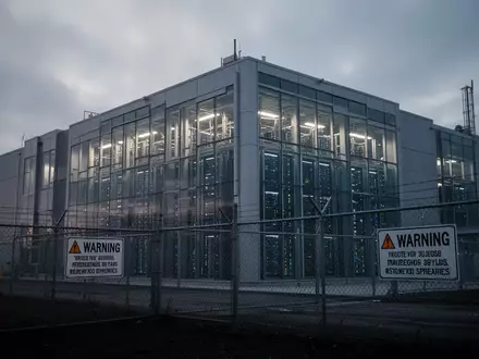 Ein modernes Rechenzentrum in der Dämmerung mit sichtbaren Serverräumen hinter Glasfassaden in einer Industrieumgebung. - Foto: über boerse-global.de