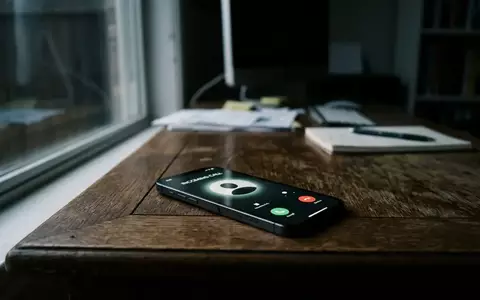 Ein modernes Smartphone liegt auf einem Schreibtisch und zeigt einen eingehenden Anruf in einer professionellen Büroumgebung. - Foto: über boerse-global.de