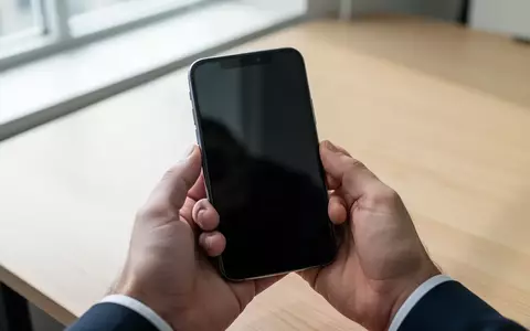 Nahaufnahme einer Person, die ein modernes Smartphone in einem minimalistischen Büro hält. - Foto: über boerse-global.de