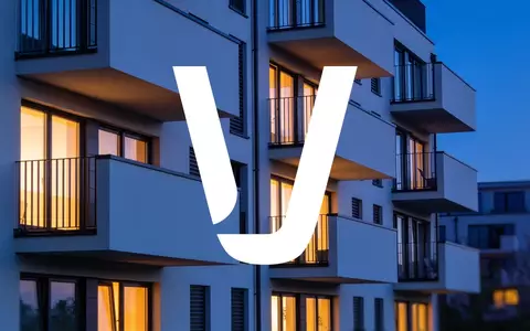 Moderne Wohnhausfassade in der Dämmerung mit warm beleuchteten Fenstern und minimalistischer Architektur. - Foto: über boerse-global.de