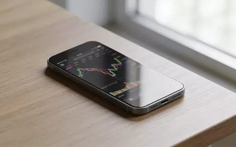 Ein minimalistischer Schreibtisch mit einem Smartphone, das einen unscharfen Aktienchart anzeigt. - Foto: über boerse-global.de