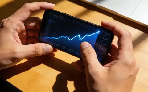 Nahaufnahme einer Person, die auf einem Smartphone einen steil ansteigenden Finanzchart betrachtet. - Foto: über boerse-global.de