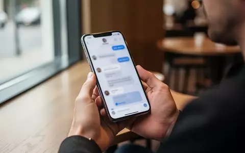 Person hält ein Smartphone in einem modernen Café und nutzt eine Messenger-App. - Foto: über boerse-global.de