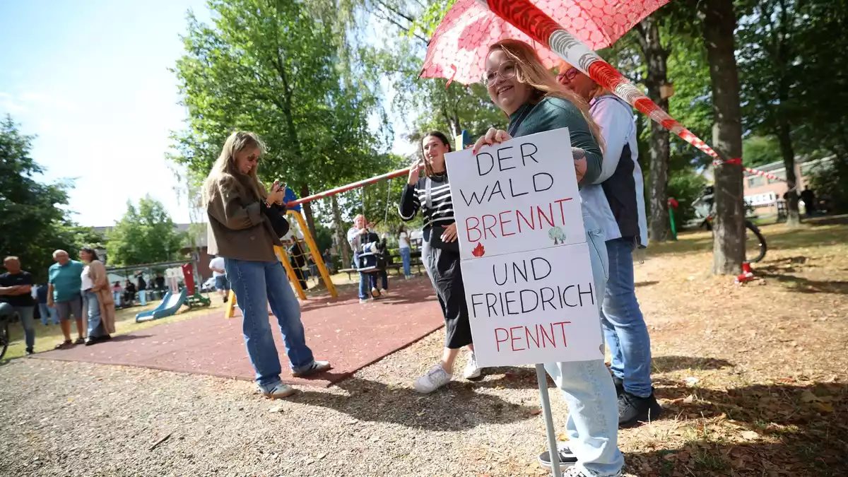 Demonstranten protestierten unter anderem mit einem Plakat, auf dem «Der Wald brennt und Friedrich pennt» stand.  - Bild: Christoph Reichwein/dpa
