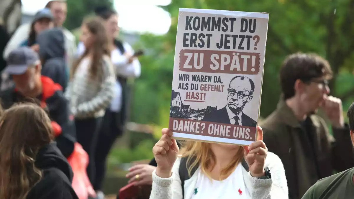 Demonstranten warfen Merz vor, erst nach Ende der Löscharbeiten den Brandort aufzusuchen.  - Bild: Christoph Reichwein/dpa