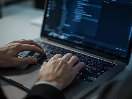 Nahaufnahme von Händen an einer Laptop-Tastatur in einem Büro, symbolisch für die Gefahr durch Phishing-Angriffe. - Foto: über boerse-global.de