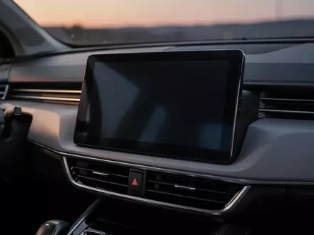 Nahaufnahme eines modernen Auto-Infotainment-Bildschirms in einem dunklen Fahrzeuginnenraum bei Dämmerung. - Foto: über boerse-global.de