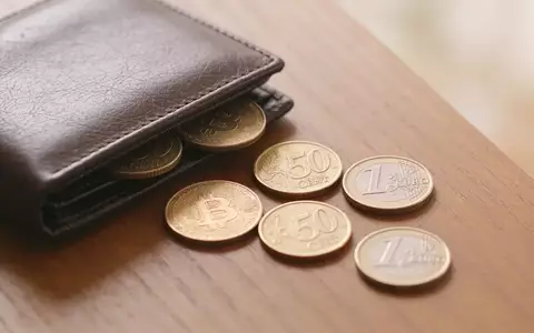 Nahaufnahme einer minimalistischen Schreibtischoberfläche mit einer Geldbörse und einigen verstreuten Münzen bei natürlichem Licht. - Foto: über boerse-global.de