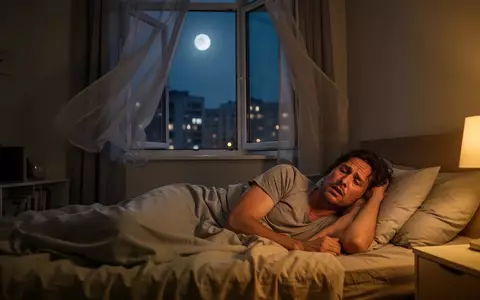 Eine unruhige Person liegt in einem nächtlich beleuchteten Schlafzimmer während einer heißen Sommernacht. - Foto: über boerse-global.de