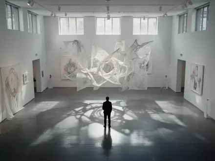 Eine einzelne Person betrachtet eine abstrakte Lichtinstallation in einem minimalistischen Kunstmuseum. - Foto: über boerse-global.de