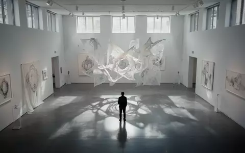 Eine einzelne Person betrachtet eine abstrakte Lichtinstallation in einem minimalistischen Kunstmuseum. - Foto: über boerse-global.de