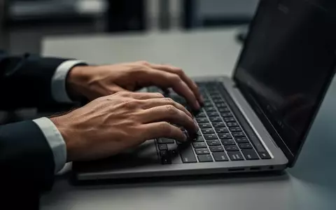 Hände beim Tippen auf einer Laptop-Tastatur in einer professionellen Büroumgebung mit stimmungsvoller Beleuchtung. - Foto: über boerse-global.de