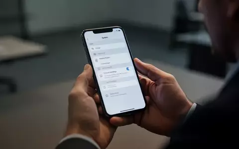 Nahaufnahme einer Person, die ein modernes Smartphone in einem Büro hält, während sie komplexe Systemeinstellungen prüft. - Foto: über boerse-global.de