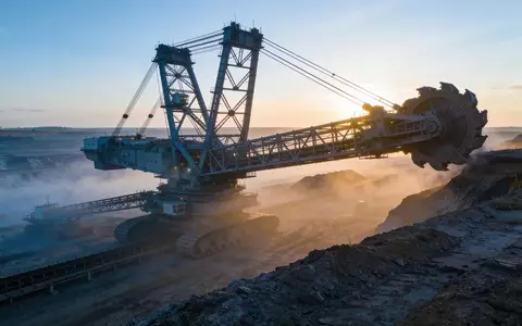 Industrielles Bergbaugelände bei Morgendämmerung mit schweren Maschinen in einer nebligen Landschaft. - Foto: über boerse-global.de