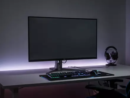 Ein moderner Gaming-Monitor auf einem Schreibtisch in einem dezent beleuchteten Raum. - Foto: über boerse-global.de