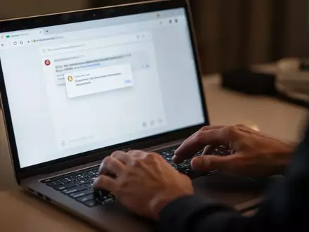 Nahaufnahme einer Person am Laptop, die vorsichtig eine verdächtige E-Mail betrachtet, um Phishing zu verdeutlichen. - Foto: über boerse-global.de