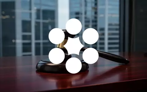 Ein Anwaltsrichterhammer auf einem dunklen Schreibtisch vor einem unscharfen Bürogebäude, symbolisiert rechtliche Schritte. - Foto: über boerse-global.de