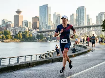 Ein Triathlet läuft während eines Wettkampfs entlang einer städtischen Uferpromenade bei Sonnenaufgang. - Foto: über boerse-global.de