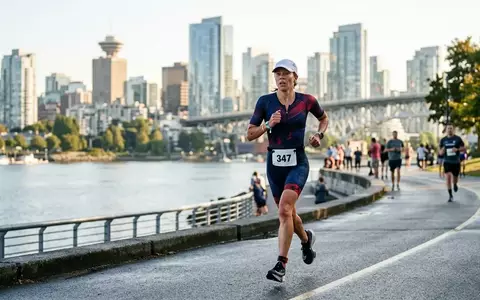 Ein Triathlet läuft während eines Wettkampfs entlang einer städtischen Uferpromenade bei Sonnenaufgang. - Foto: über boerse-global.de