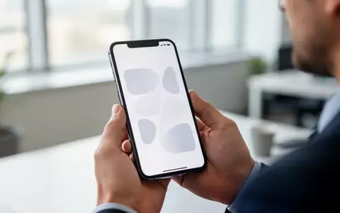 Ein Smartphone in einer Hand vor einem verschwommenen Büro-Hintergrund, symbolisch für die Regulierung sozialer Medien. - Foto: über boerse-global.de