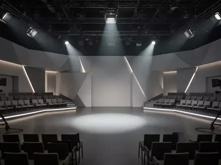 Leeres, modern gestaltetes Fernsehstudio mit geometrischen Elementen und dramatischer Beleuchtung. - Foto: über boerse-global.de