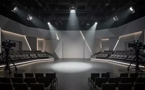 Leeres, modern gestaltetes Fernsehstudio mit geometrischen Elementen und dramatischer Beleuchtung. - Foto: über boerse-global.de
