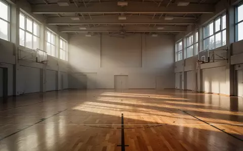 Leere, lichtdurchflutete Sporthalle mit Parkettboden und großen Fensterfronten. - Foto: über boerse-global.de