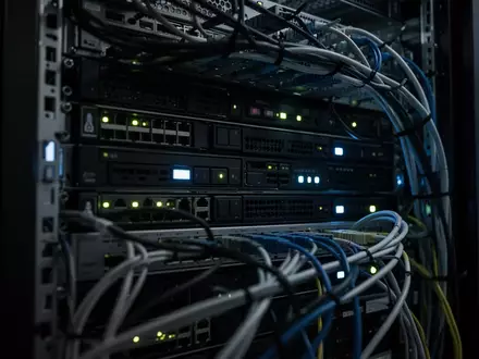 Dunkler Serverraum mit blinkenden LEDs an moderner Hardware und komplexer Verkabelung in einer professionellen IT-Umgebung. - Foto: über boerse-global.de