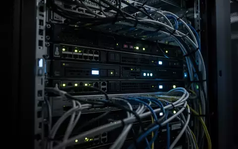 Dunkler Serverraum mit blinkenden LEDs an moderner Hardware und komplexer Verkabelung in einer professionellen IT-Umgebung. - Foto: über boerse-global.de