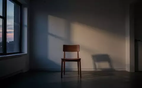 Ein leerer Raum mit einem Stuhl vor einem Fenster bei Dämmerung, der eine Atmosphäre der emotionalen Wandlung vermittelt. - Foto: über boerse-global.de