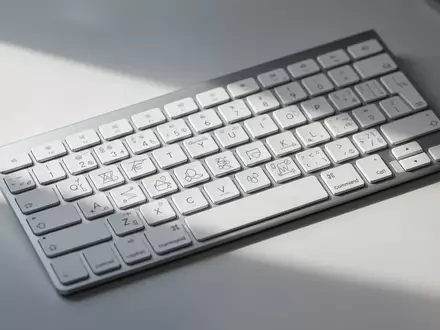Ein weißes Apple Magic Keyboard auf einem Schreibtisch mit Tasten, die statt Textbeschriftung abstrakte Symbole zeigen. - Foto: über boerse-global.de