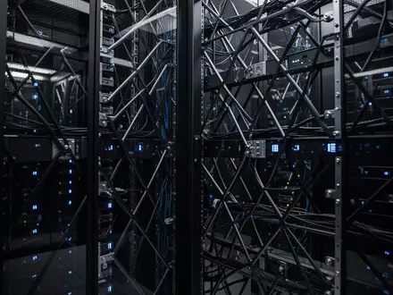 Dunkler Serverraum mit modernen Computer-Racks und blauer Beleuchtung als Symbol für digitale Infrastruktur. - Foto: über boerse-global.de