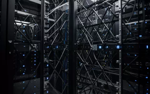Dunkler Serverraum mit modernen Computer-Racks und blauer Beleuchtung als Symbol für digitale Infrastruktur. - Foto: über boerse-global.de