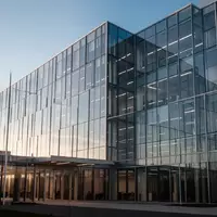 Moderne Glasfassade eines Bürogebäudes bei Tageslicht, die Transparenz und unternehmerische Strukturen symbolisiert. - Foto: über boerse-global.de