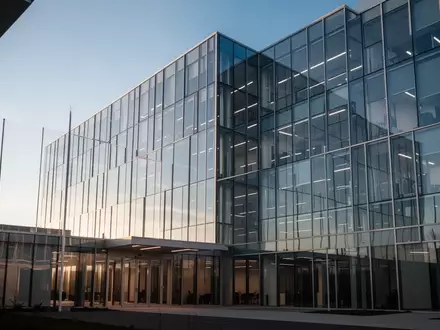 Moderne Glasfassade eines Bürogebäudes bei Tageslicht, die Transparenz und unternehmerische Strukturen symbolisiert. - Foto: über boerse-global.de