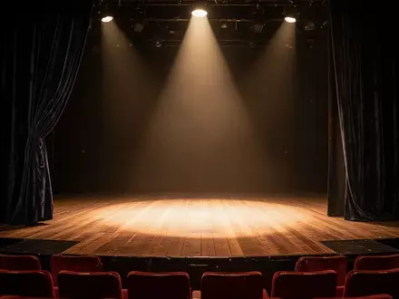 Eine leere Theaterbühne mit Holzboden und einem dezent beleuchteten Vorhang in einem ruhigen, atmosphärischen Raum. - Foto: über boerse-global.de