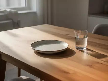 Ein leerer Teller und ein Glas Wasser auf einem Holztisch in einem hellen, skandinavischen Raum. - Foto: über boerse-global.de