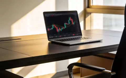 Ein moderner Schreibtisch mit einem Laptop, auf dem ein verschwommener Finanzchart zu sehen ist, bei natürlichem Licht. - Foto: über boerse-global.de