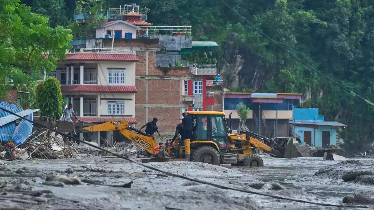 Rettungskräfte setzen Baumaschinen ein, um unter Wasser stehende Häuser nach Sturzfluten zu erreichen. - Bild: Niranjan Shrestha/AP/dpa