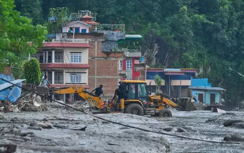 Rettungskräfte setzen Baumaschinen ein, um unter Wasser stehende Häuser nach Sturzfluten zu erreichen. - Foto: Niranjan Shrestha/AP/dpa