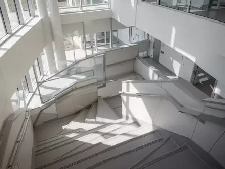Ein minimalistisches, helles Treppenhaus in einem modernen Klinikgebäude mit klaren architektonischen Linien und natürlichem Licht. - Foto: über boerse-global.de