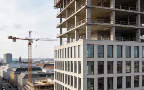 Halbfertiges Bürogebäude in einer deutschen Großstadt mit Baukran bei Tageslicht. - Foto: über boerse-global.de