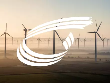 Moderne Windkraftanlagen in einer weiten, nebligen Landschaft bei Sonnenaufgang. - Foto: über boerse-global.de