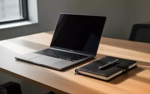 Ein moderner, aufgeräumter Arbeitsplatz mit einem Laptop, dessen Bildschirm ausgeschaltet ist, einem Notizbuch und einem Stift bei natürlichem Tageslicht. - Foto: über boerse-global.de