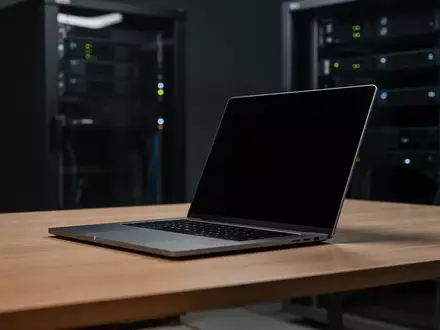 Ein moderner, dunkler Arbeitsplatz mit einem Laptop, dessen Bildschirm ausgeschaltet ist, in einem minimalistischen Büro. - Foto: über boerse-global.de