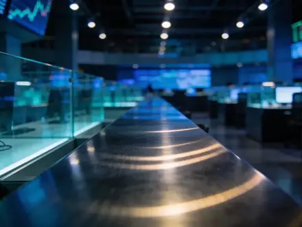 Ein moderner, dunkel gehaltener Handelsraum mit professioneller Beleuchtung und Fokus auf eine reflektierende Oberfläche. - Foto: über boerse-global.de
